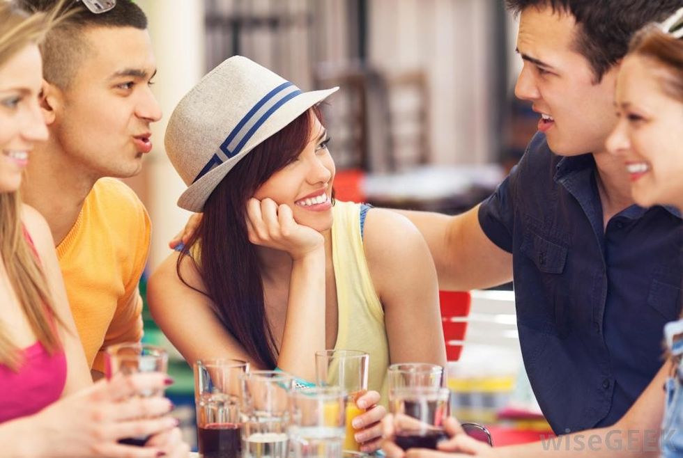 five people smiling at each other at table