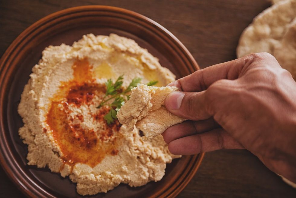 hand dipping pita bread hummus