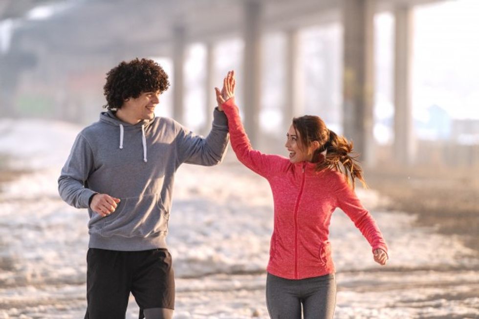 happy caucasian runners giving high five during running cold weather snow all