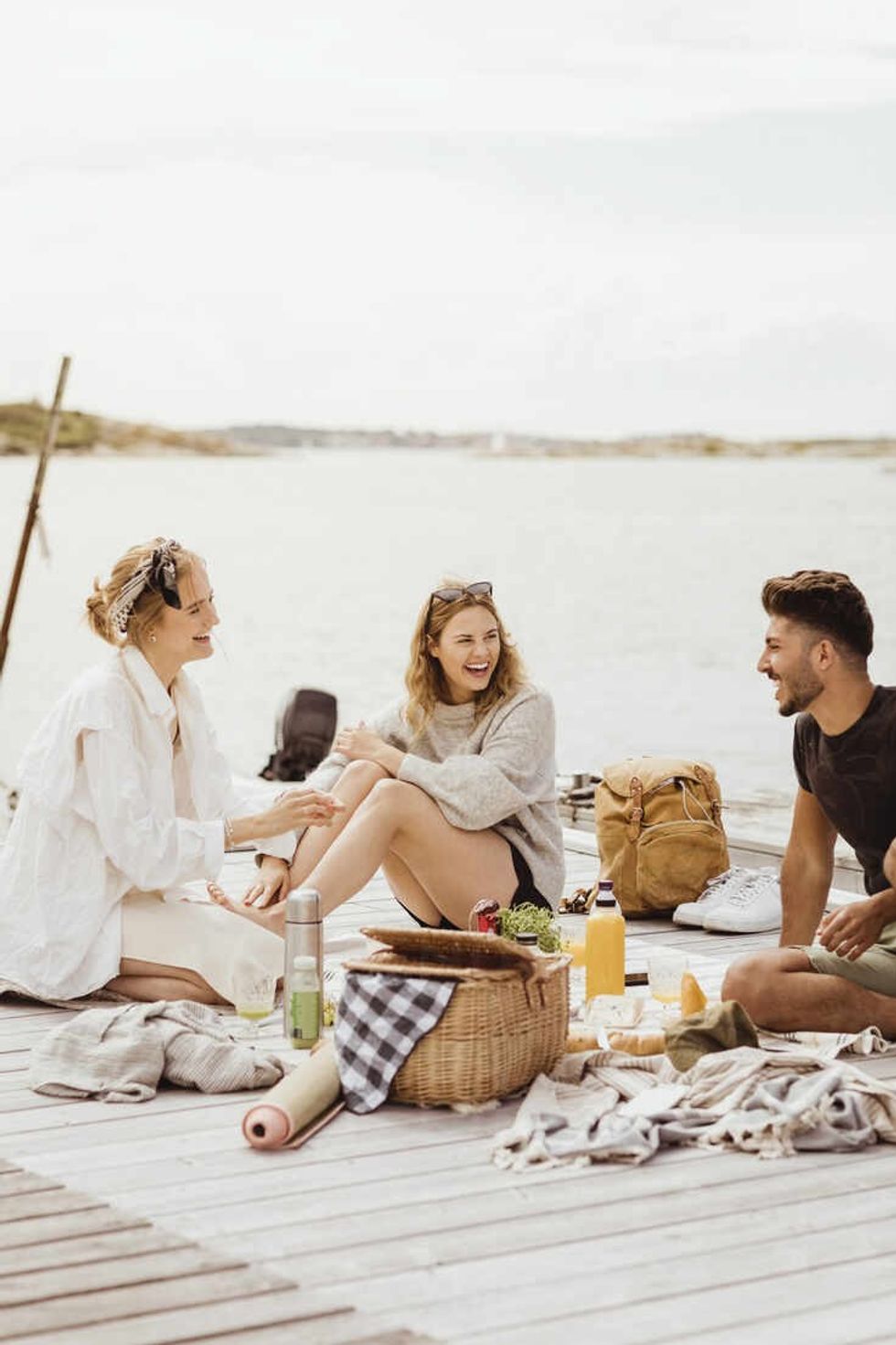 happy young friends spending leisure time while sitting on jetty against sky and sea MASF21759