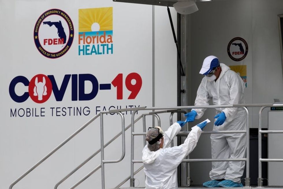 Health care workers work at a walk-up COVID-19 testing site during the coronavirus pandemic, Friday, July 17, 2020, in Miami