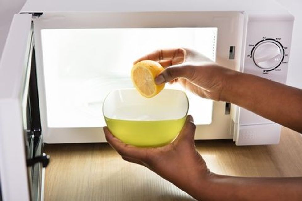 human hand putting sliced lemon in bowl