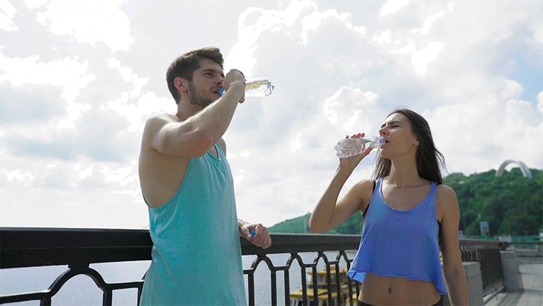 2018/07/friendship-and-lifestyle-concept-smiling-sporty-couple-having-a-break-with-bottles-of-water-at-city-bridge-river-as-background_hfgiwfdso__F0000.jpg
