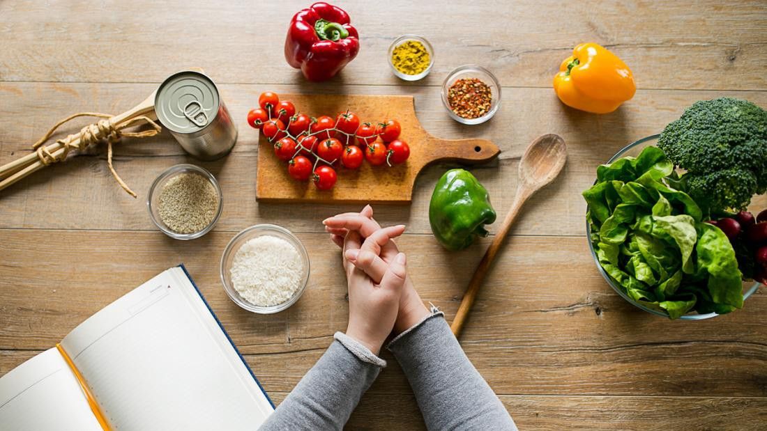 2018/07/woman-leaning-on-table-with-various-ingredients-and-a-diet-planning-book.jpg