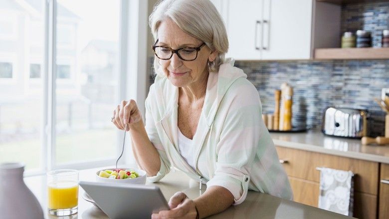2020/04/1492003135-woman-eating-fruit-salad-reading-ipad.jpg