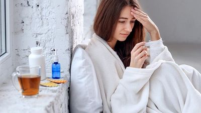 2020/08/ill-woman-with-headache-sore-throat-fever-covered-blanket-feeling-sick-e1596530789709.jpg