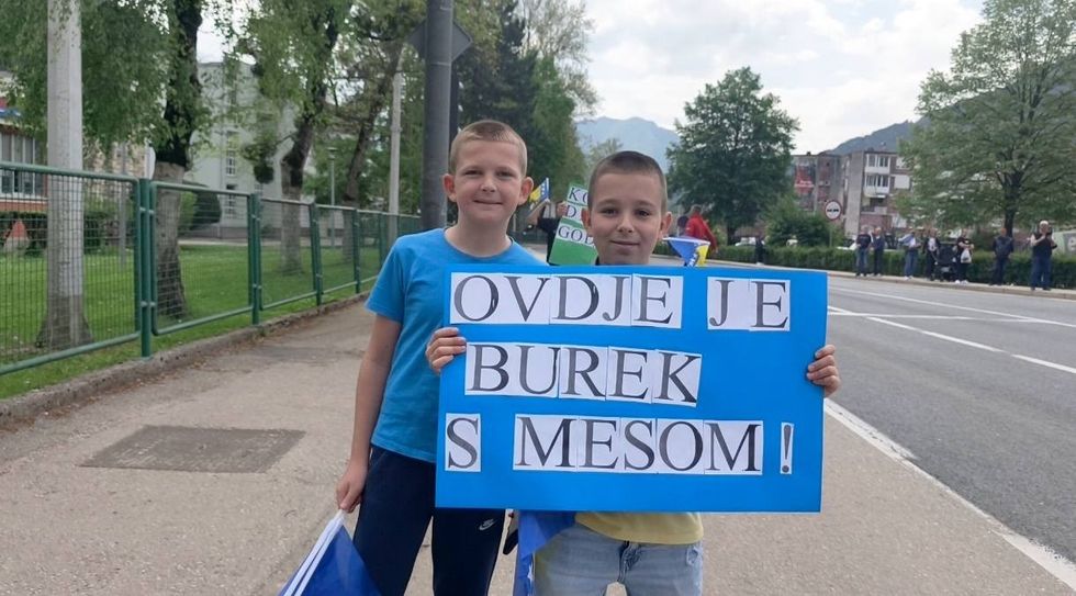 “Këtu ka burek me mish!” – disa fëmijë janë bërë viralë me pankartat e tyre kreative gjatë një gare në Bosnjë