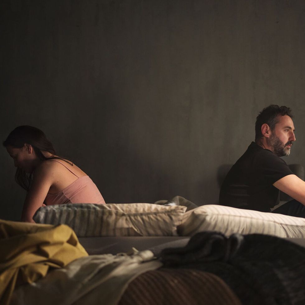 Jealous betrayed woman with her husband sitting back to back in bed 1