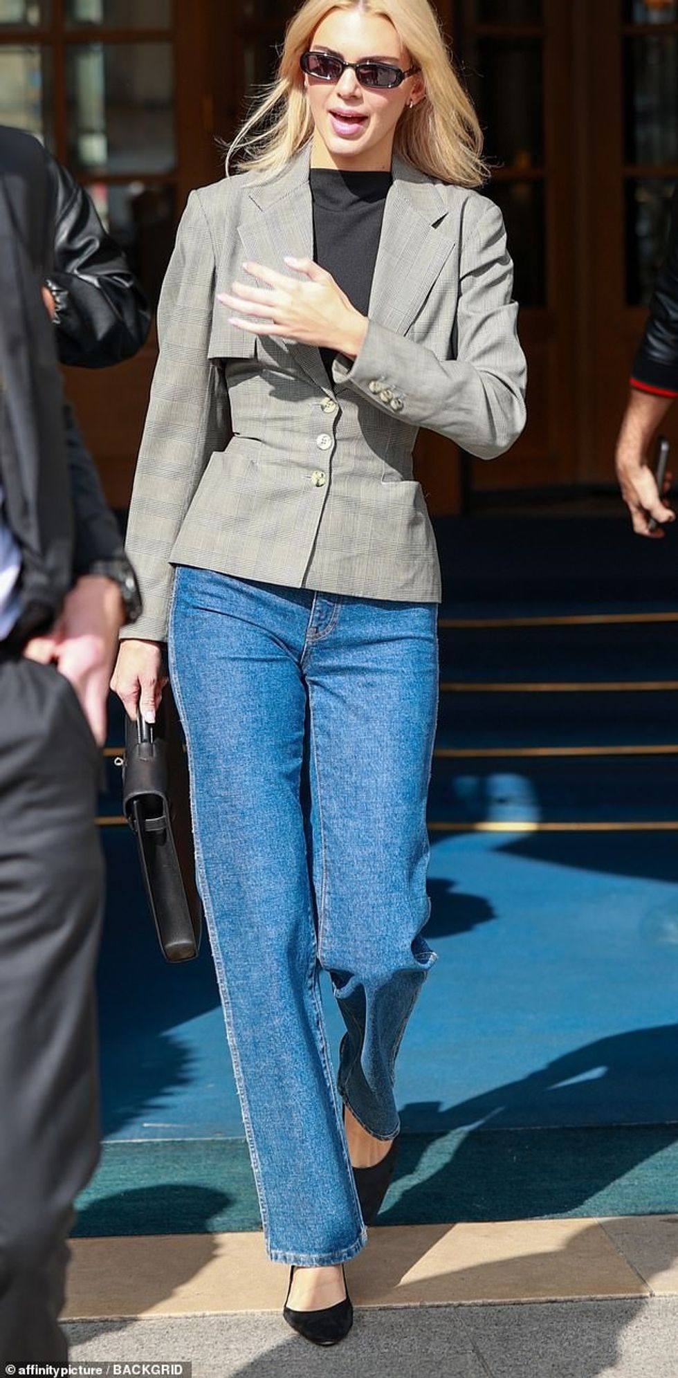 Kendall accessorised with a satchel-style black handbag, black narrow-frame sunglasses and a delicate pair of silver hoop earrings