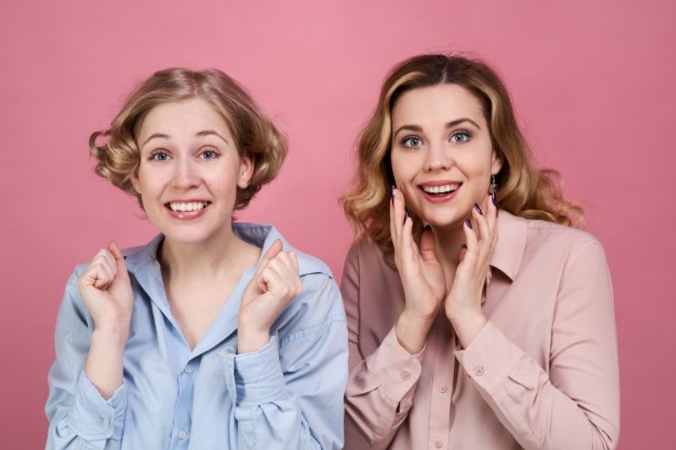 large studio portrait two young cheerful girls shirts with wide smile cheering enthusiastically hold