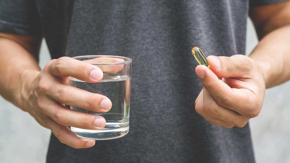 man holding omega 3 and water