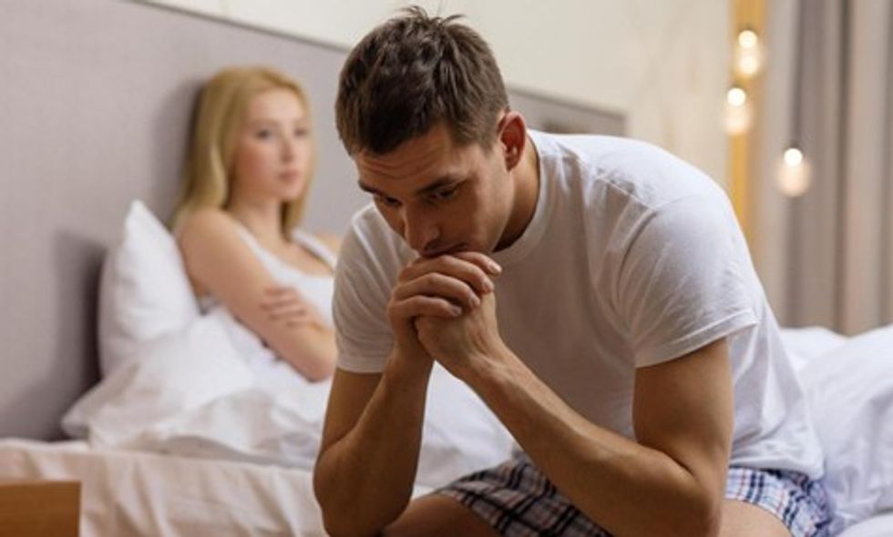 man looking worried sitting on bed with woman