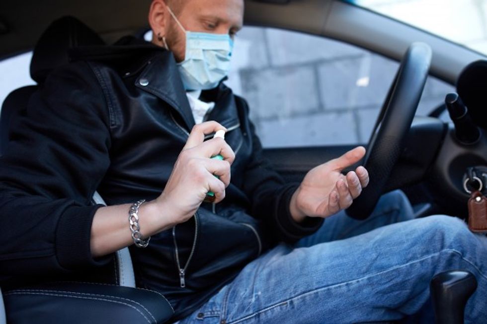 man protection mask sitting car spraying hands antibacterial sanitizer sp
