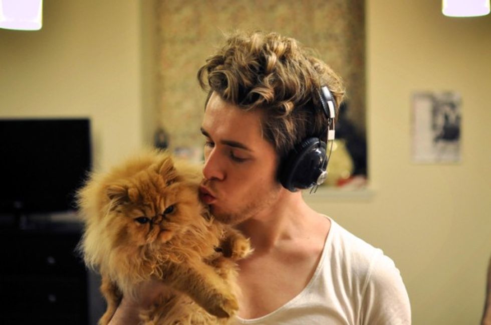 Man wearing headphones holding with cat