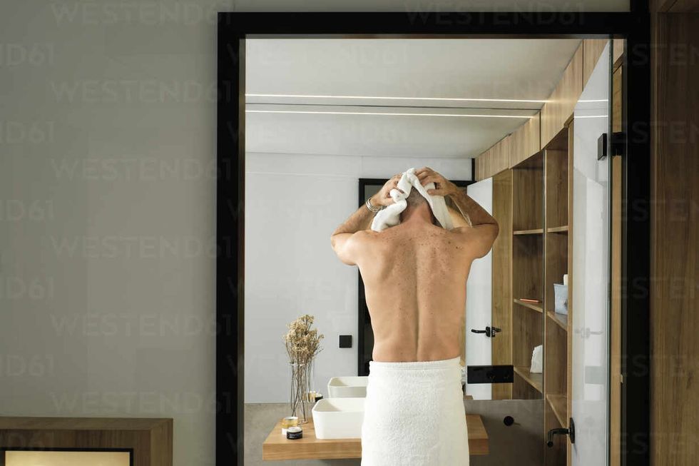 mature man wearing towel drying hair in bath