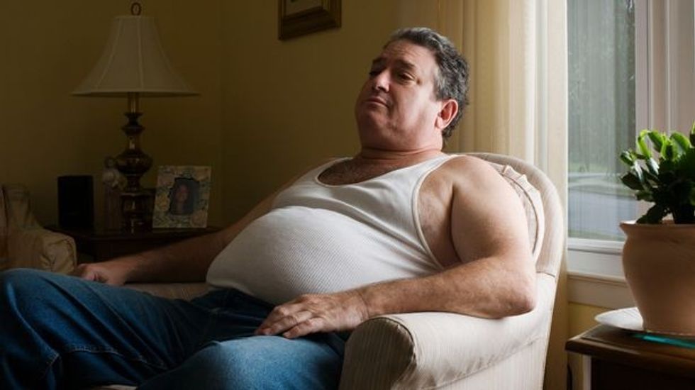 Mature overweight man sitting in armchair