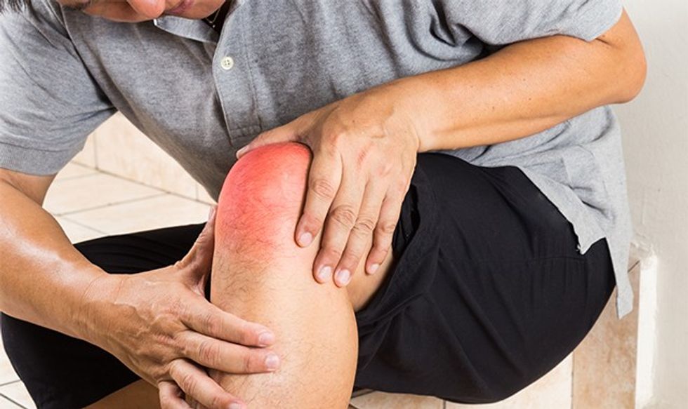 Matured man suffering from painful knee joint seated on steps