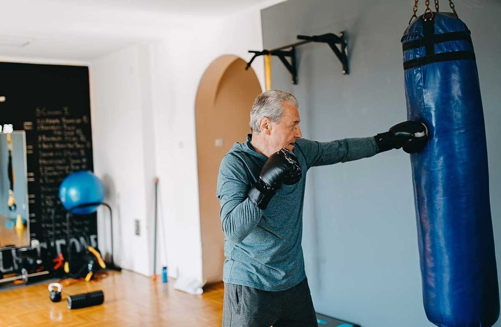 middle aged causaian man punching a punching bag