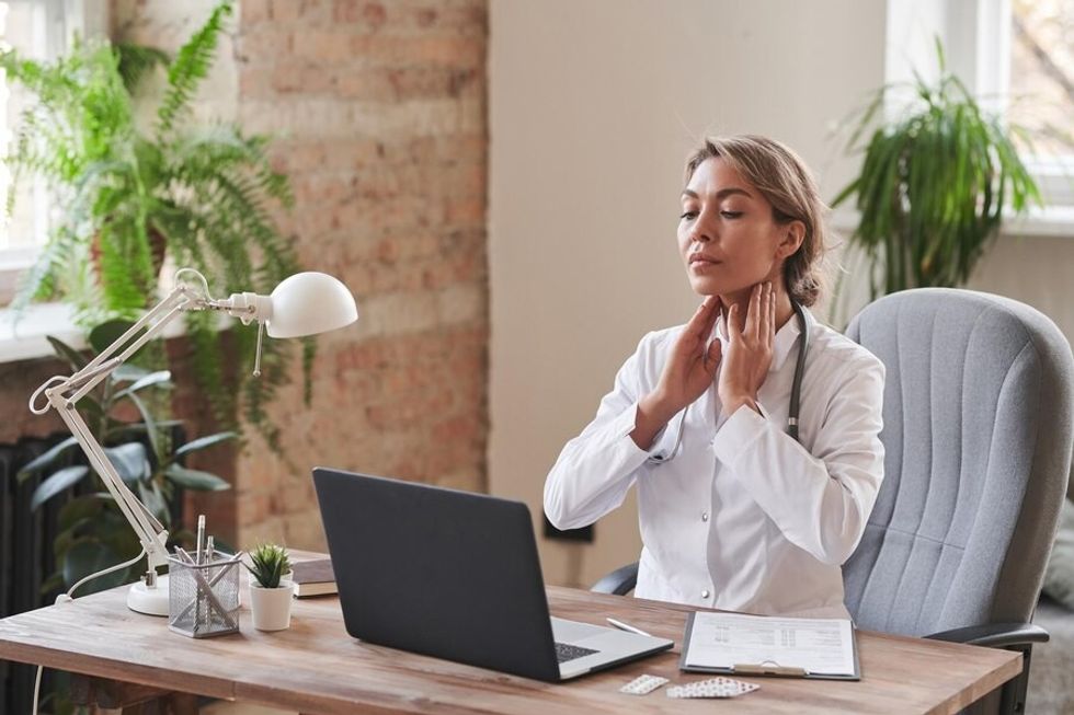 modern female doctor sitting desk office demonstrating how palpate neck lymph no