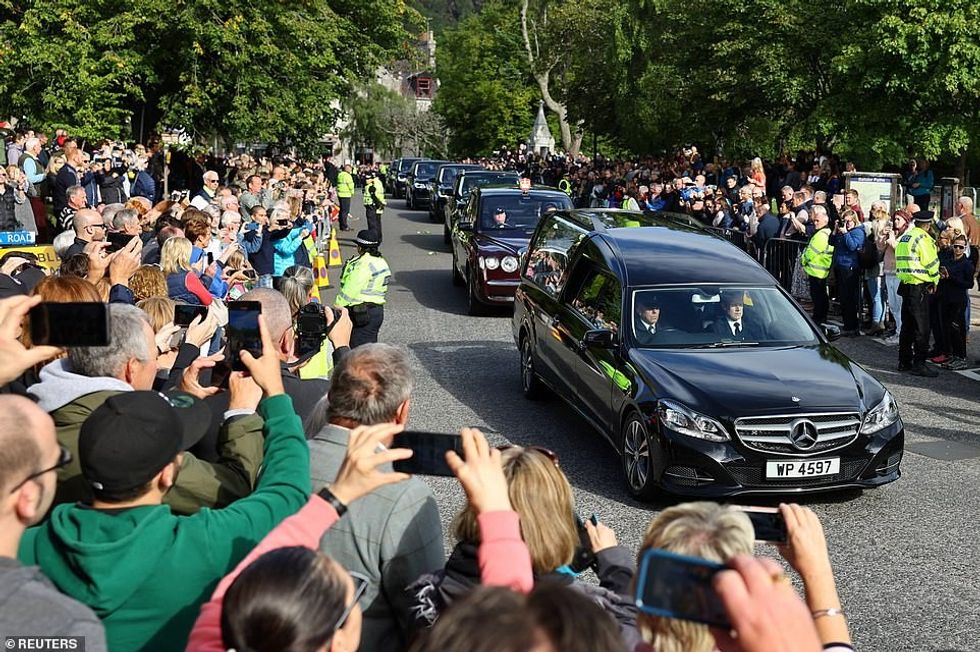 Most people stood in silence as the convoy passed through the village of Ballater, while others filmed the moment on their phones
