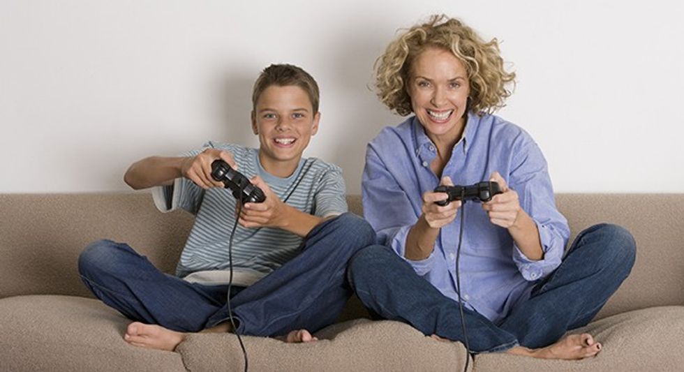 Mother and son (13-15) playing with game controls, smiling