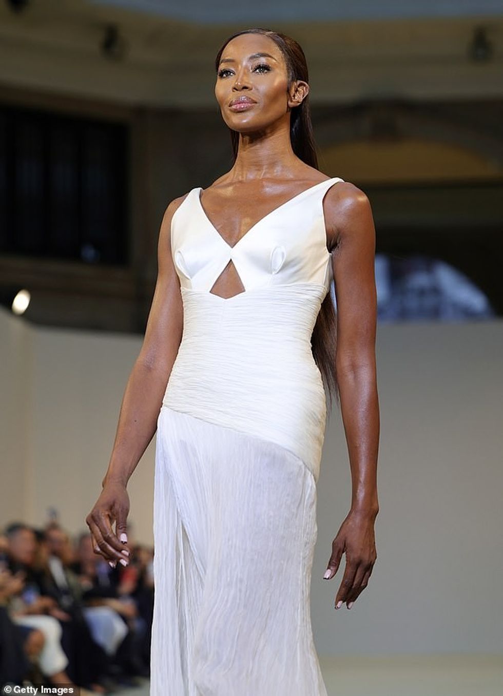 Naomi veshi fustanet e saj të gjata të errëta në një dorezë të pastër të mbështjellë pas veshëve