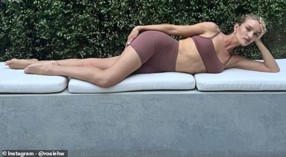 Një tjetër pa Rosie të shtrirë në një divan në natyrë e veshur me një komplet yoga në ngjyrë vjollce me një majë pa mëngë të prera ekstra dhe pantallona të shkurtra për çiklizëm