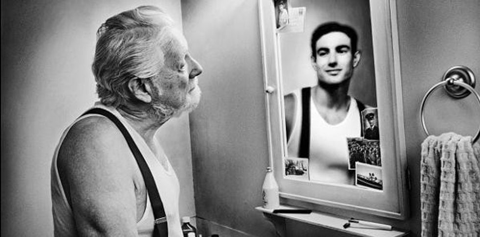 old man looking at younger reflection