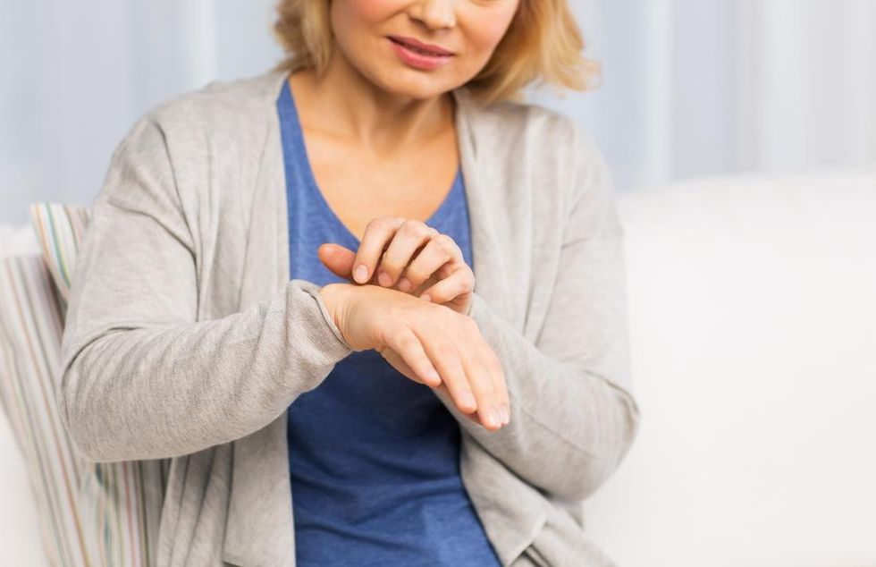 older woman scratching her hand with a menopause rash