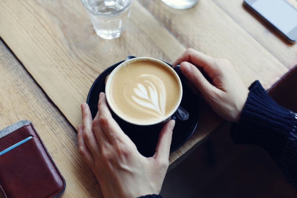 overhead shot hands holding cup of coffee at table