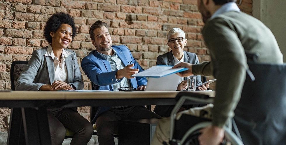 panel interviewing man wheelchair istock 1206394273
