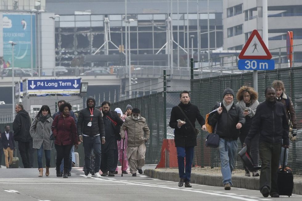 Passengers leave Brussels airport, on March 22, 2016 in Zaventem , following its evacuation after at least 13 people were killed and 35 injured as twin blasts rocked the main terminal of Brussels airport.AFP PHOTO / JOHN THYS / AFP / JOHN THYS (Photo credit should read JOHN THYS/AFP/Getty Images)