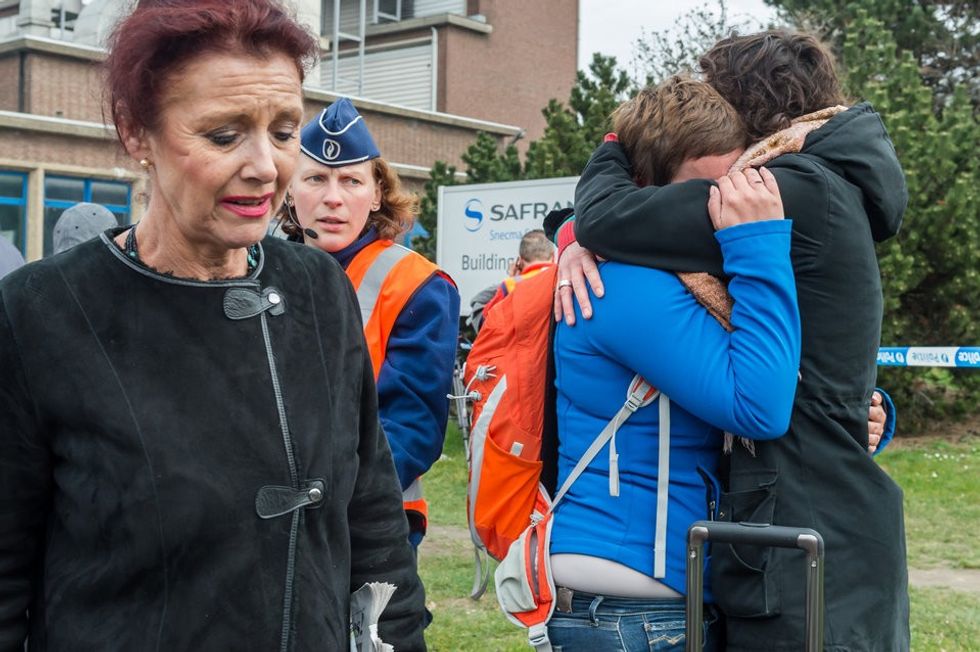 People react outside Brussels airport after explosions rocked the facility in Brussels, Belgium Tuesday March 22, 2016. Explosions rocked the Brussels airport and the subway system Tuesday, just days after the main suspect in the November Paris attacks was arrested in the city, police said. (AP Photo/Geert Vanden Wijngaert)