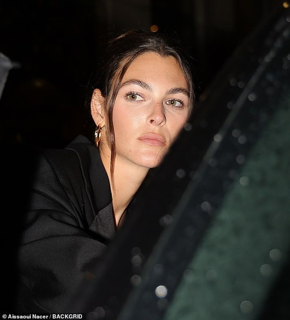 Për të përfunduar pamjen e saj të hijshme, mblodhi fijet e saj të gjata brune në një topuz dhe aksesorë me një palë rrathë floriri