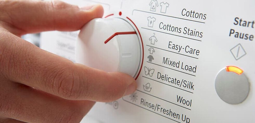 Person Turning Washing Machine Dial