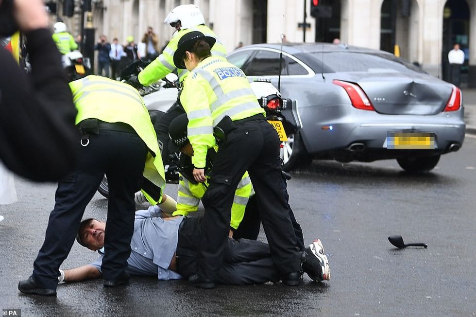Police detain a man after he ran in front of Prime Minister Boris Johnson's car as it left the Houses of Parliament today