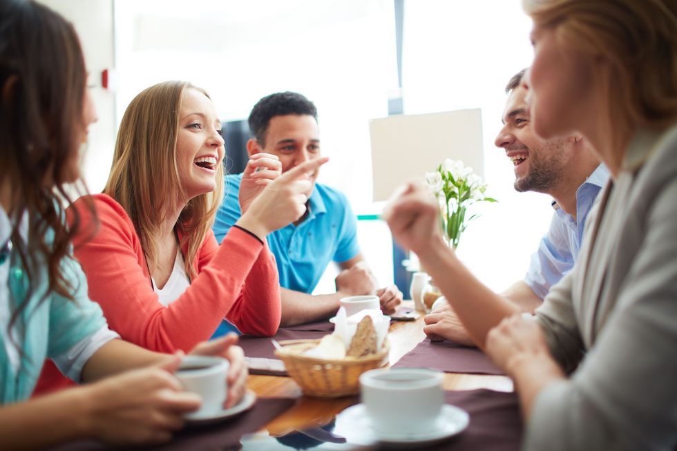 Portrait of happy teenage friends sitting and chatting in cafe