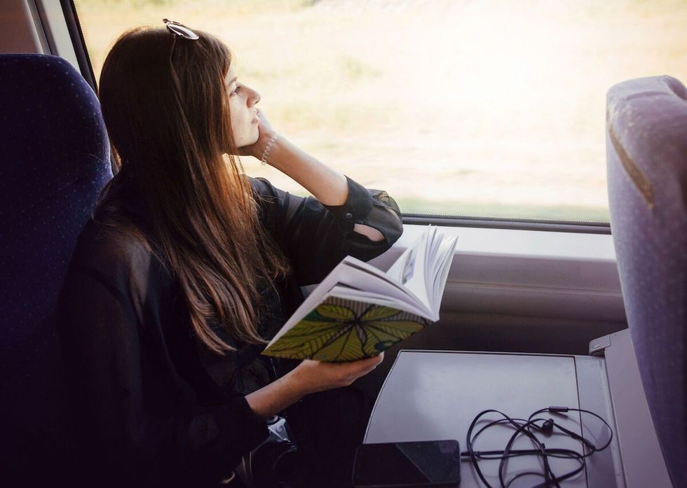 Portrait of young woman reading a book and travelling on train 1