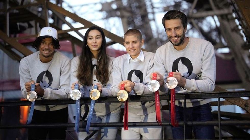 Presidenti i Komitetit Organizativ të Olimpiadës Paris 2024, Tony Estanguet, djathtas, atletet franceze Marie Patouillet, në qendër të djathtë, Sara Balzer, qendra e majtë dhe Arnaud Assoumani, majtas, prezantojnë medaljet Olimpike dhe Paraolimpike Paris 2024 në Kullën Eifel. Foto: AP