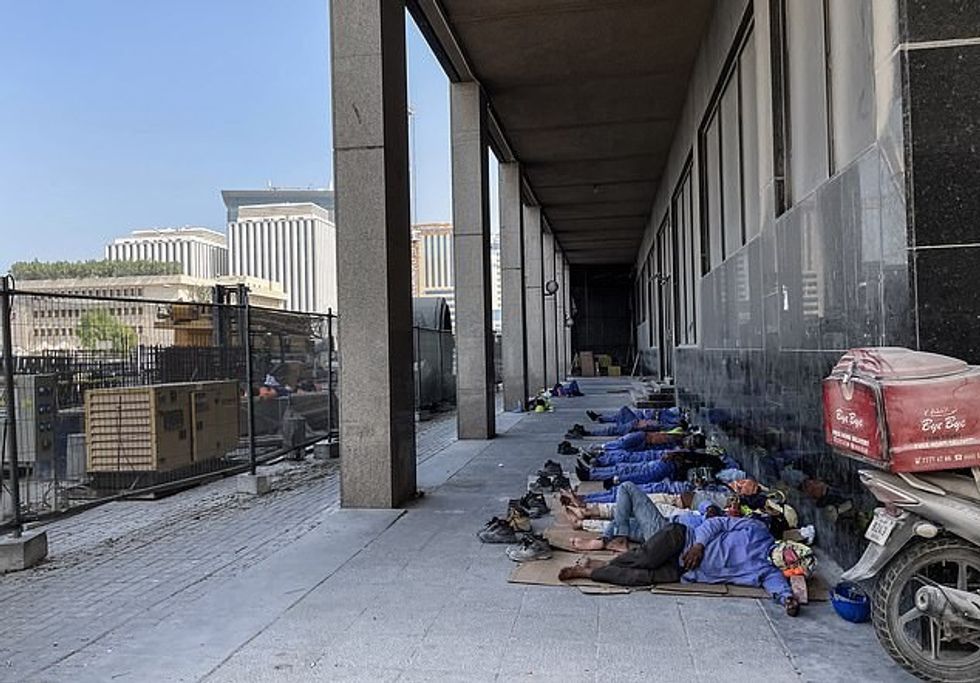 Punëtorët migrantë strehohen nga dielli në një projekt ndërtimi të Kupës së Botës në Katar - një raport i vitit të kaluar tha se 6,500 kishin vdekur duke ndërtuar infrastrukturën e turneut