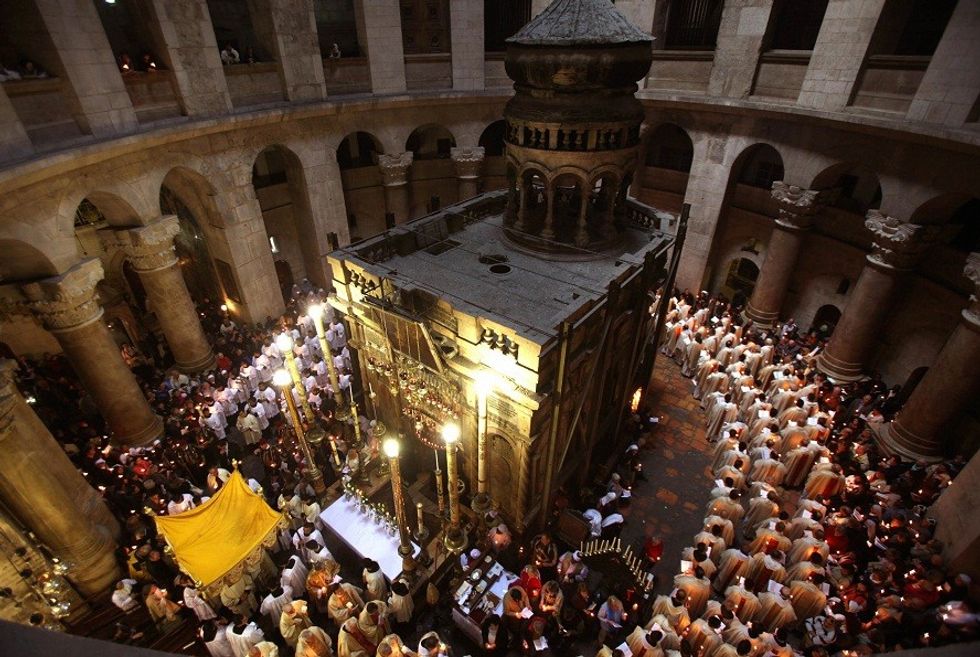 Roman Catholic clergy men hold candles as they circle the aedicule during the Holy Thursday Easter procession at the Church of the Holy Sepulchre in Jerusalem's Old City on April 09, 2009. Christian believers around the world mark the solemn period of Easter in celebration of the crucifixion and resurrection of Jesus Christ. Christians traditionally believe the church is built on the site where Jesus was crucified and buried. AFP PHOTO/GALI TIBBON (Photo credit should read GALI TIBBON/AFP/Getty Images)