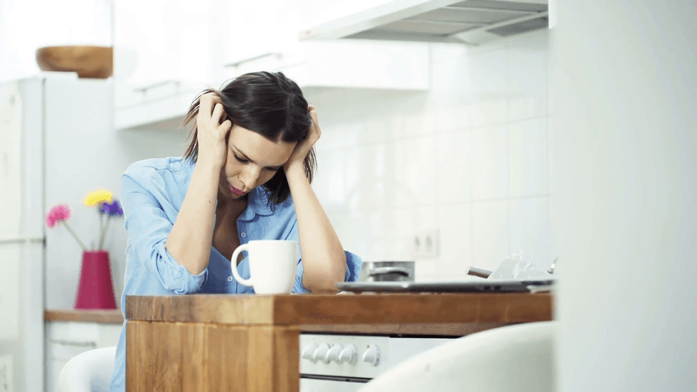 sad unhappy woman drinking coffee by table in kitchen at home ekybtlko F0000