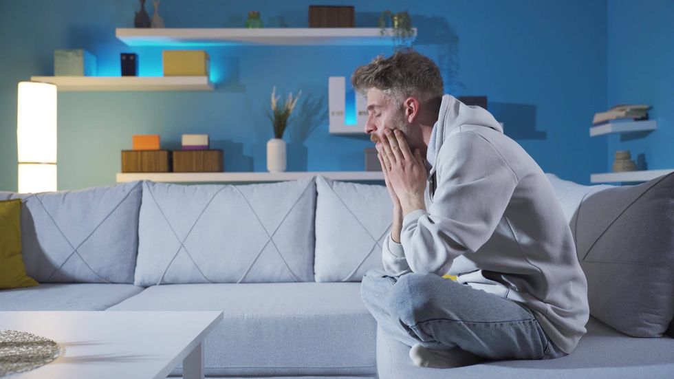 sad young man covering his face with his hands at home family depression illness dramatic bad news tram video scaled