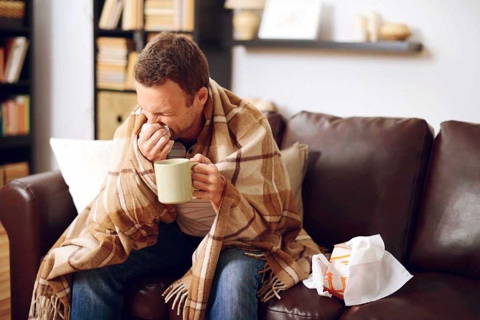 sick man on couch drinking tea