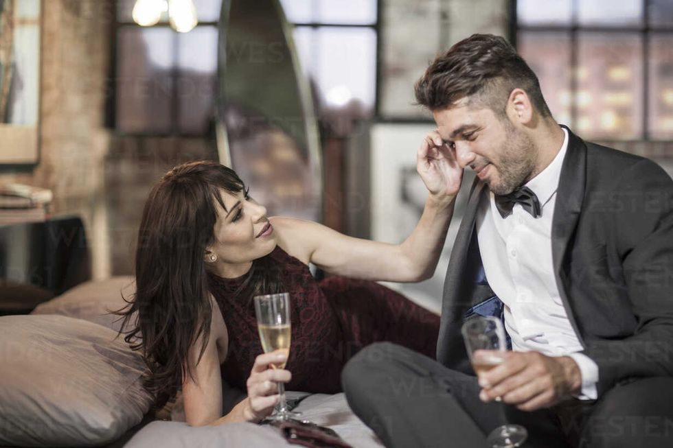 smiling couple in elegant clothing drinking champagne in bed ZEF008460