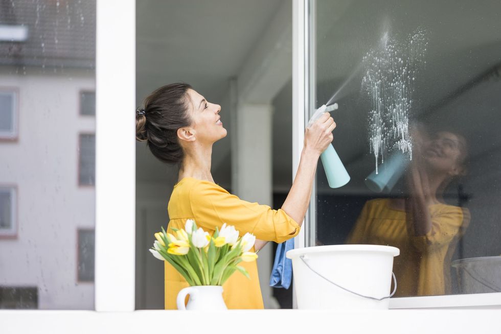 smiling woman at home cleaning the window royalty free image 934884504 1566215507