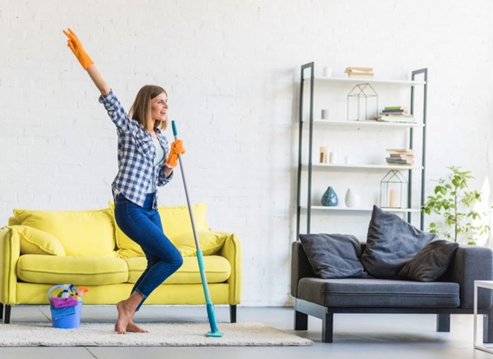 smiling young woman dancing living room with cleaning equipments 23 2147916506