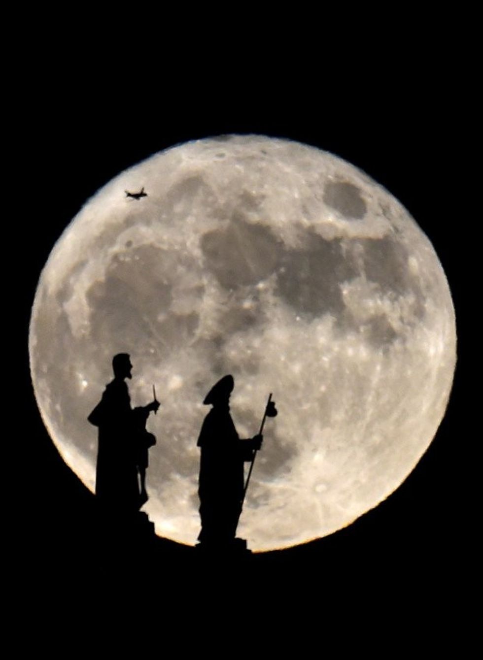 Statues on the Almudena cathedral and a plane are silhouetted against a Supermoon in Madrid on November 14, 2016. The phenomenon happens when the moon is full at the same time as, or very near, perigee -- its closest point to Earth on an elliptical, monthly orbit. It was the closest to Earth since 1948 at a distance of 356,509 kilometres (221,524 miles), creating what NASA described as