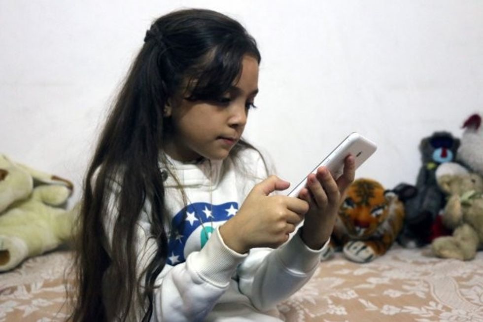 Syrian Bana al-Abed, who with the help of her mother had been posting heartrending tweets in English on life in the besieged eastern districts of Syria's Aleppo, uses a smart-phone to check her Twitter account in her home in east Aleppo, on October 12, 2016. The seven-year-old Syrian girl whose Twitter account from Aleppo gained international attention has fled her home amid heavy fighting, but she and her family are safe for now, her father said on December 6, 2016. / AFP PHOTO / THAER MOHAMMEDTHAER MOHAMMED/AFP/Getty Images