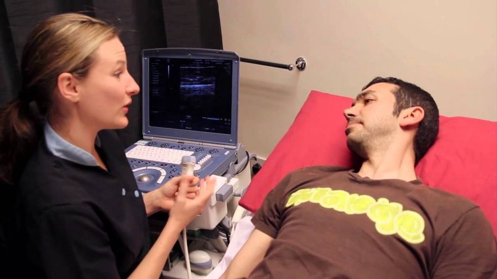 technician holding ultrasound scanner at machine to perform testicular ultrasound